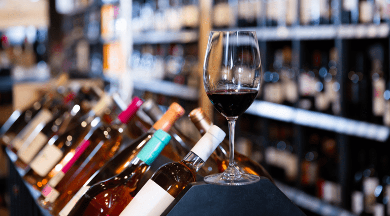 glass of wine sitting on a shelf in a local bottle and wine shop