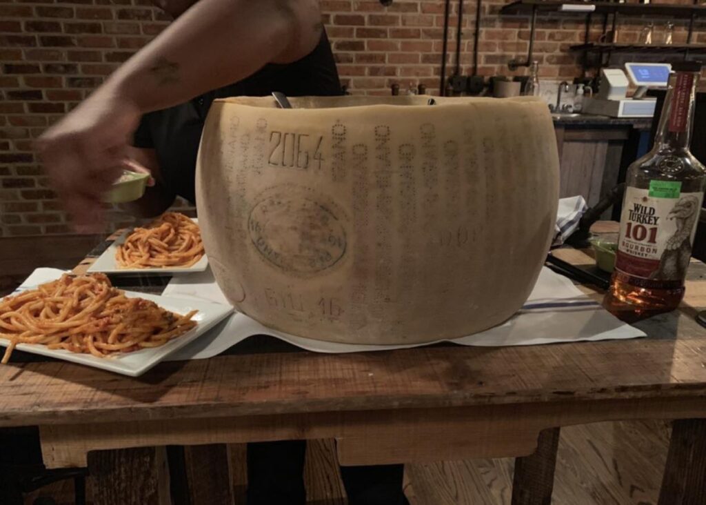 waiter serving spaghetti out of a giant parmesan cheese wheel, Tarantelli's restaurant date night spot in Downtown Wilmington