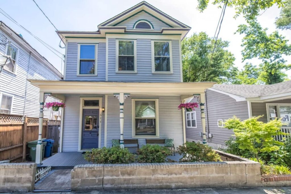 Exterior of N'awlins House, an Airbnb hosted by Wilmington Vacation Homes. Blue with flowers and porch. New Orleans themed