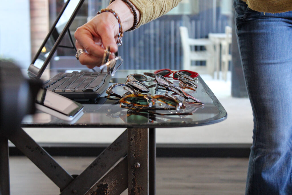 Woman perusing eyeglass frames on a table. CustomEyes, Wilmington, NC